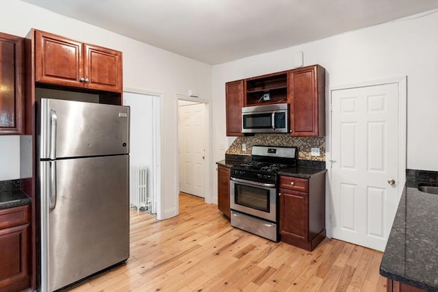 kitchen featuring radiator, open shelves, light wood-style flooring, decorative backsplash, and appliances with stainless steel finishes