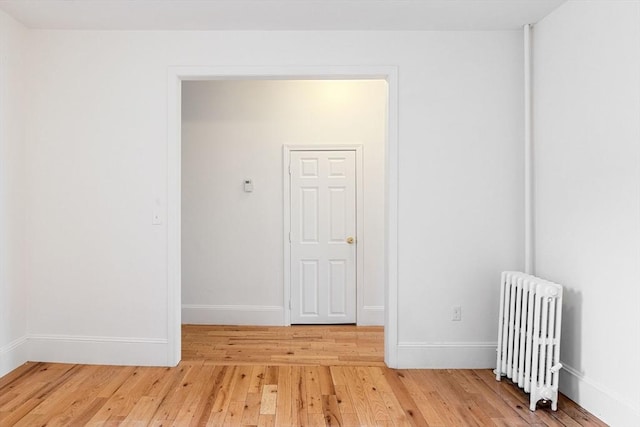 spare room with light wood-style flooring, radiator heating unit, and baseboards