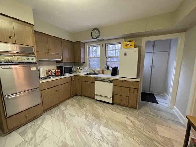 kitchen with stainless steel microwave, oven, light countertops, white dishwasher, and a sink