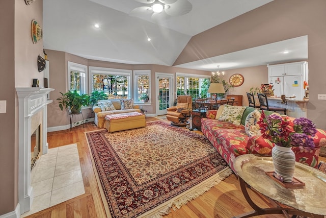 living room featuring lofted ceiling, ceiling fan with notable chandelier, and light wood-type flooring