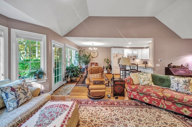 living room featuring a chandelier, vaulted ceiling, and light hardwood / wood-style floors