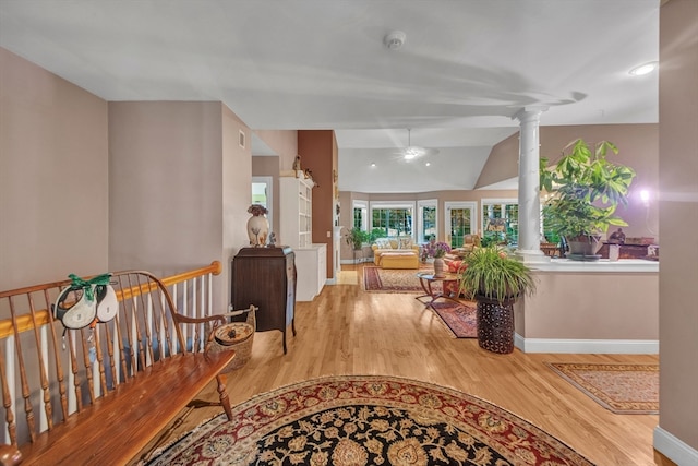 corridor featuring ornate columns, wood-type flooring, and lofted ceiling