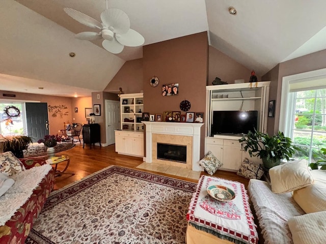 living room with ceiling fan, high vaulted ceiling, a fireplace, and hardwood / wood-style floors