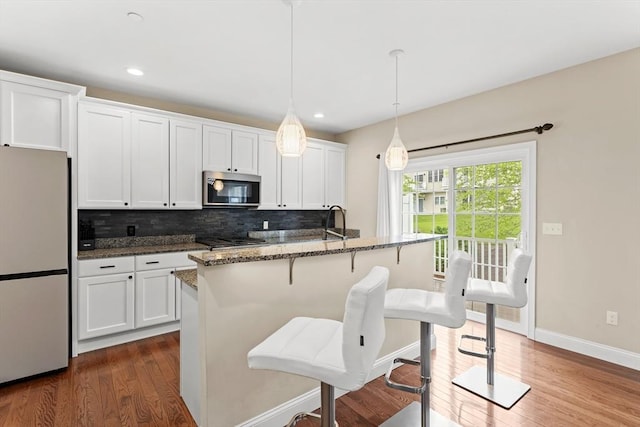 5 Manor Dr Unit B, Hooksett, NH 03106 - kitchen with freestanding refrigerator, stainless steel microwave, tasteful backsplash, dark wood-type flooring, and dark stone countertops