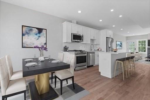 kitchen featuring white cabinets, light countertops, light wood finished floors, stainless steel appliances, and a kitchen island