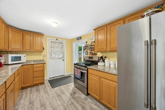 8 Stones Corner Rd, Berlin, MA 01503 - kitchen with stainless steel appliances, light wood finished floors, light stone counters, and brown cabinetry
