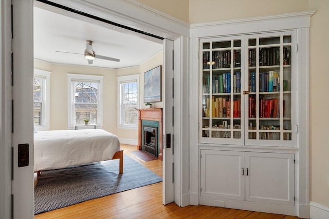 bedroom with hardwood / wood-style flooring, a fireplace with flush hearth, and ceiling fan