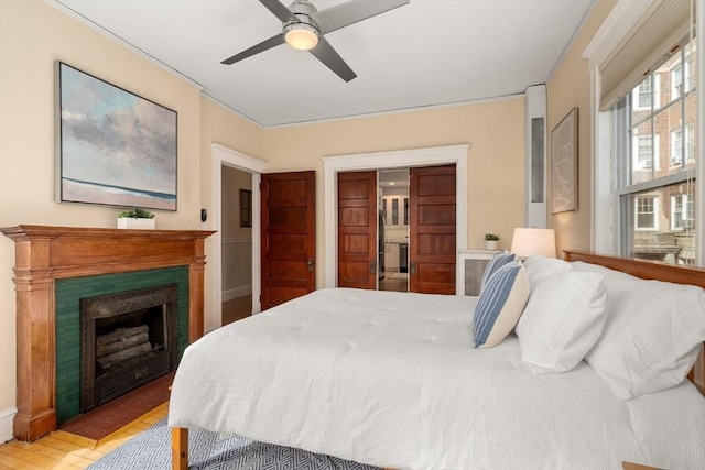 bedroom featuring a ceiling fan, a fireplace, and light wood-style flooring