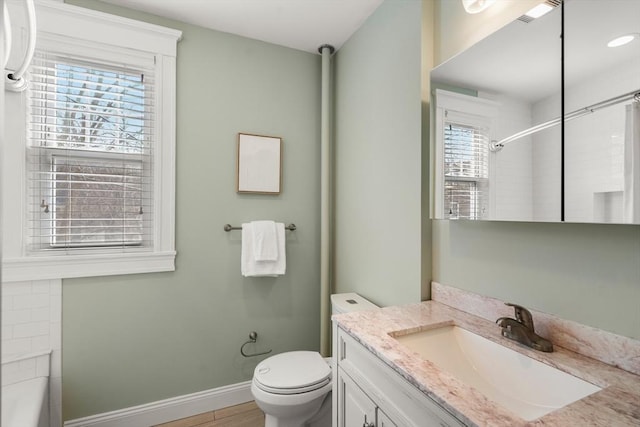 bathroom featuring baseboards, a shower, toilet, wood finished floors, and vanity