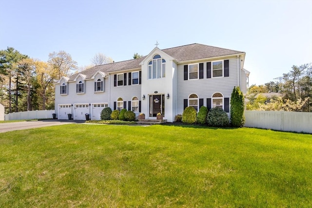view of front facade featuring fence, an attached garage, driveway, and a front lawn