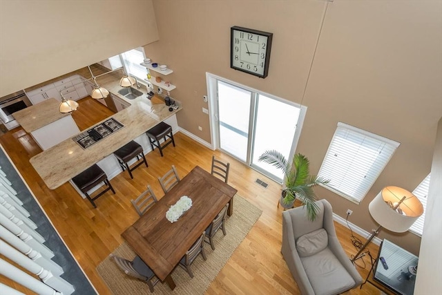 living room featuring visible vents, baseboards, a towering ceiling, and wood finished floors