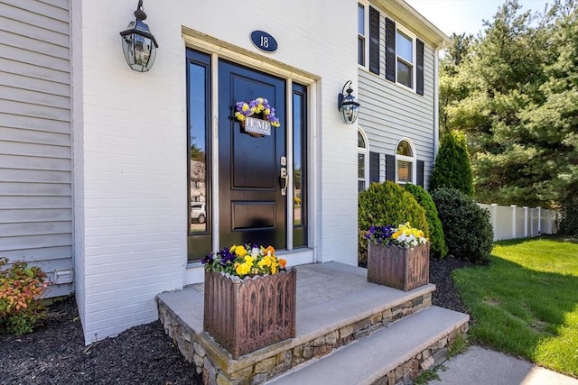view of exterior entry featuring a yard and fence