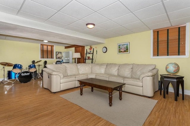 living area featuring baseboards, a paneled ceiling, and light wood-type flooring