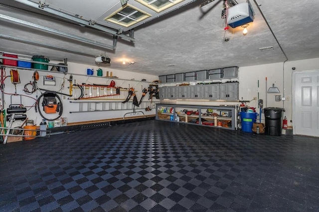 garage with visible vents, a garage door opener, and a workshop area