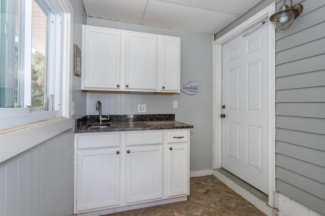 interior space featuring a sink, dark stone counters, and white cabinets