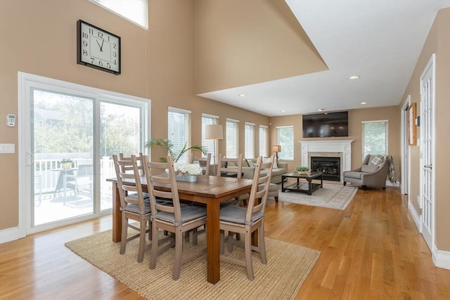 dining space with light wood-style floors, recessed lighting, baseboards, and a glass covered fireplace