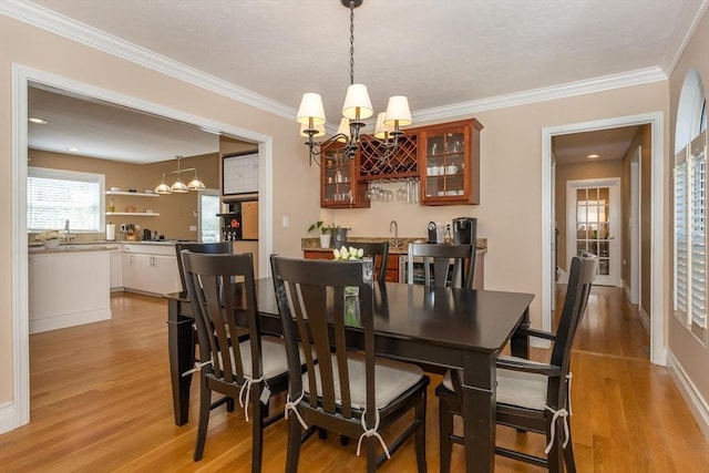 dining room with crown molding, a notable chandelier, and light wood finished floors
