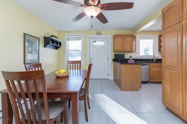 kitchen with brown cabinets, a sink, dark countertops, light tile patterned floors, and dishwasher