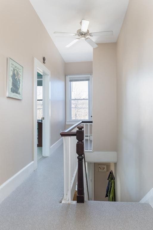 hall with an upstairs landing, carpet, and baseboards