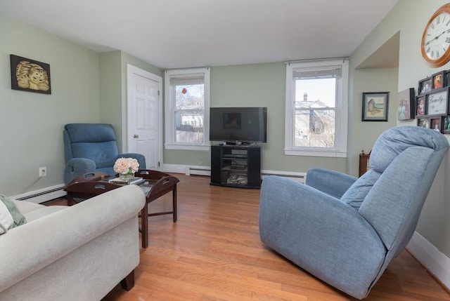 living area featuring light wood-style flooring, a baseboard heating unit, and baseboards