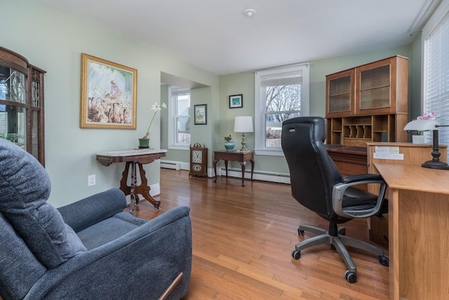 home office with baseboard heating, a baseboard heating unit, baseboards, and wood finished floors