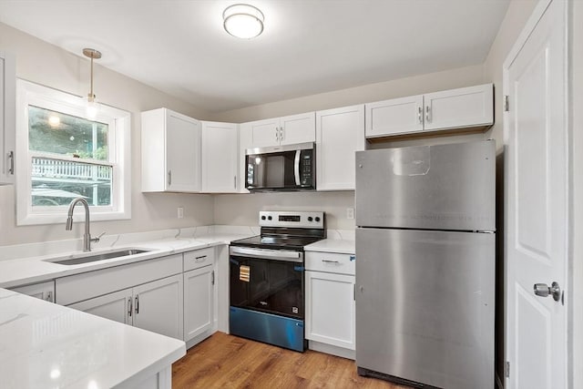 2 Howe Ter Unit 11, Boston, MA 02125 - kitchen featuring stainless steel appliances, a sink, white cabinetry, light wood-style flooring, and hanging light fixtures