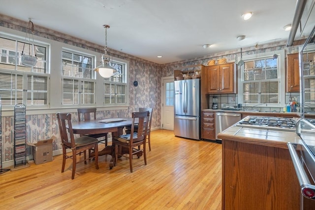46 Central Ave, Newton, MA 02460 - kitchen with tile counters, wallpapered walls, brown cabinetry, and appliances with stainless steel finishes