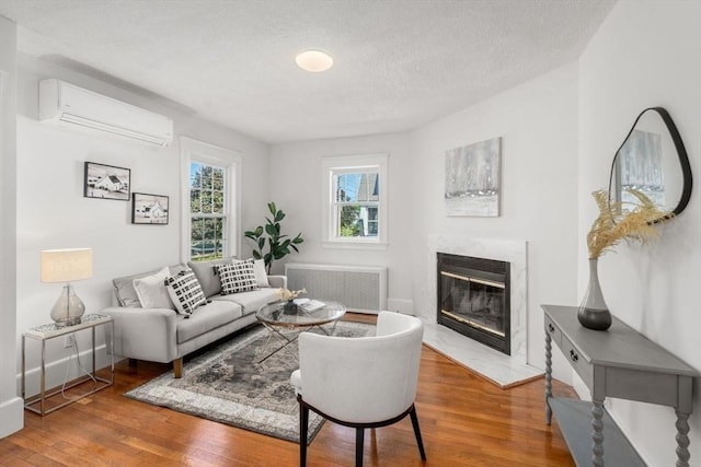 28 Saltonstall Rd, North Andover, MA 01845 - living room featuring radiator, an AC wall unit, wood finished floors, a fireplace, and a textured ceiling