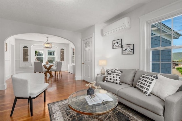 28 Saltonstall Rd, North Andover, MA 01845 - living area with arched walkways, a wall unit AC, wood finished floors, baseboards, and a chandelier