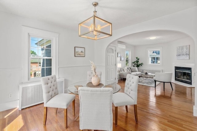 28 Saltonstall Rd, North Andover, MA 01845 - dining area featuring arched walkways, wood finished floors, a chandelier, and a glass covered fireplace