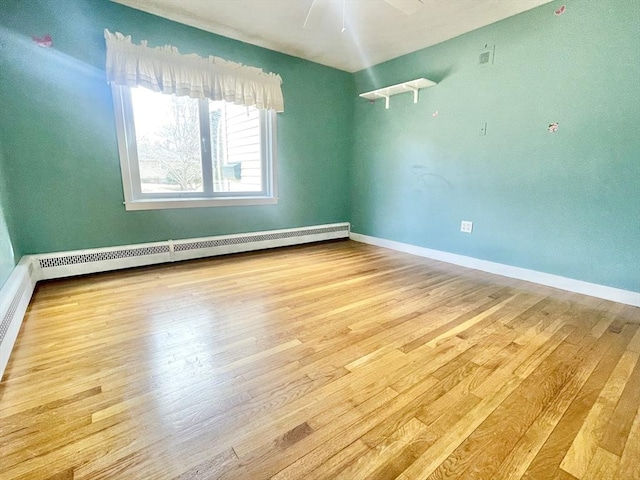 empty room featuring baseboards, baseboard heating, and wood finished floors