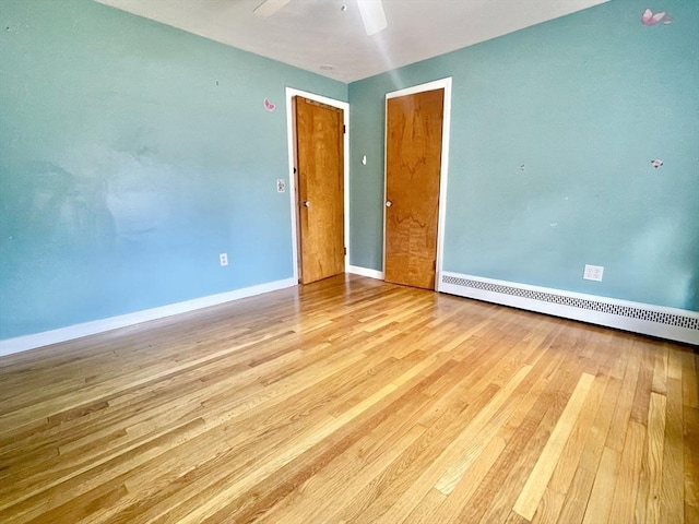 unfurnished room featuring a ceiling fan, a baseboard radiator, baseboards, and wood finished floors