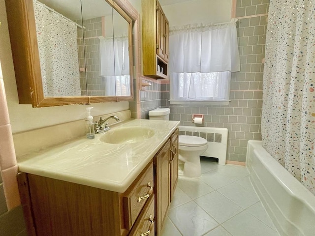 bathroom with radiator, toilet, tile patterned floors, vanity, and tile walls