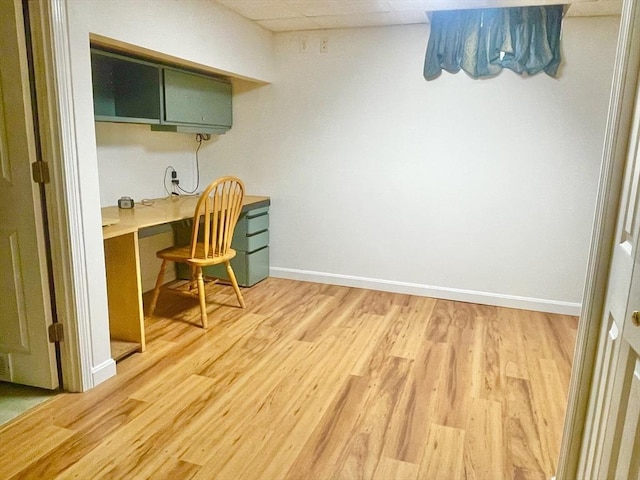 home office featuring light wood-style flooring, built in desk, and baseboards