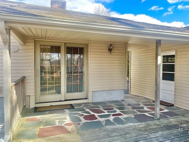 entrance to property featuring a shingled roof and a chimney