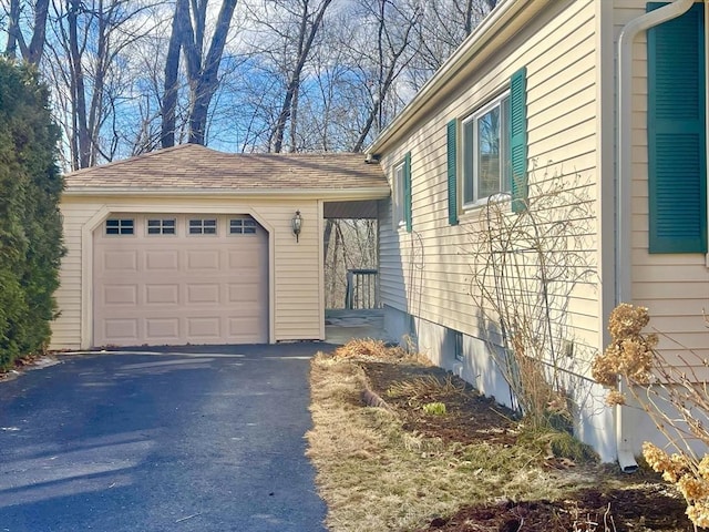 view of home's exterior with a garage, an outbuilding, driveway, and a shingled roof