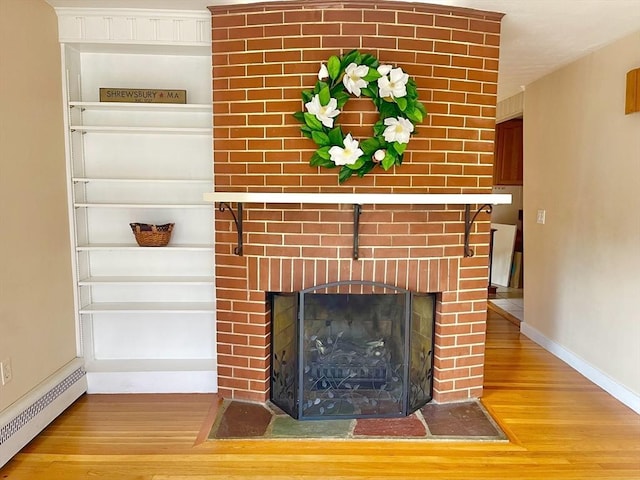 interior details featuring a baseboard radiator, a brick fireplace, baseboards, and wood finished floors