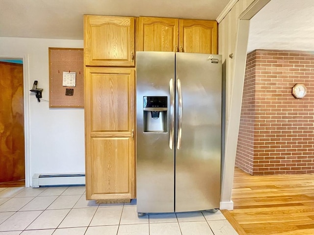 kitchen with light tile patterned floors, brick wall, a baseboard heating unit, and stainless steel fridge with ice dispenser