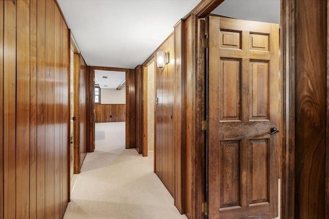 hall with light colored carpet and wooden walls