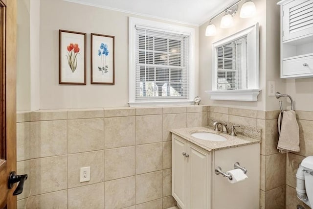 bathroom with vanity, tile walls, toilet, and a wainscoted wall