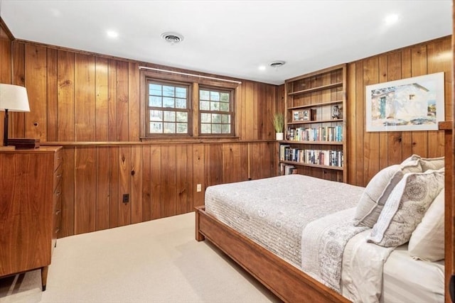 carpeted bedroom with visible vents and wood walls