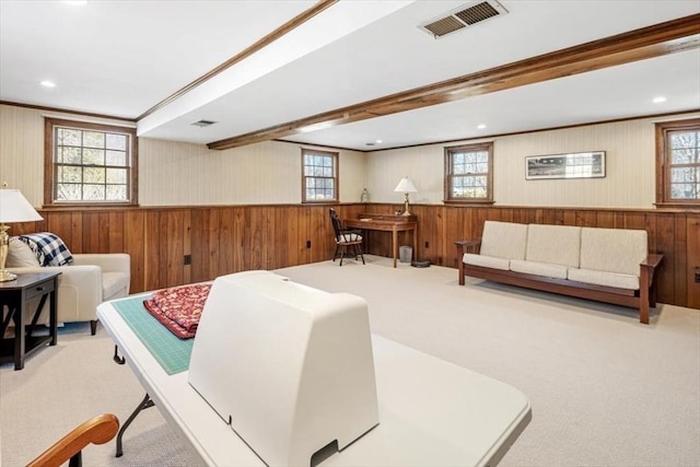 carpeted living area with visible vents, wooden walls, and a wainscoted wall