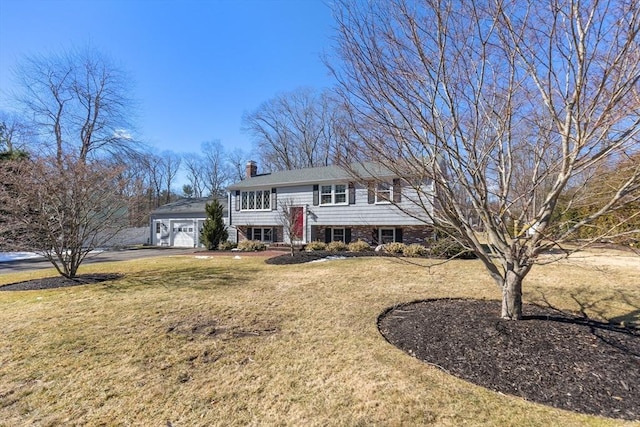 split foyer home with a chimney, a front yard, aphalt driveway, and a garage