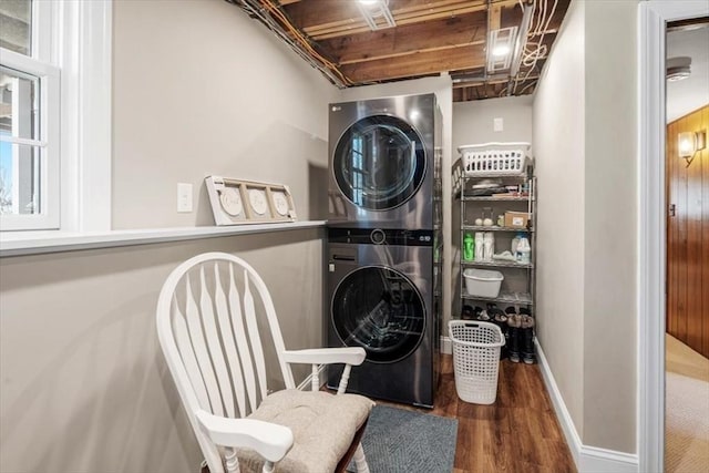 washroom with laundry area, stacked washer / dryer, wood finished floors, and baseboards