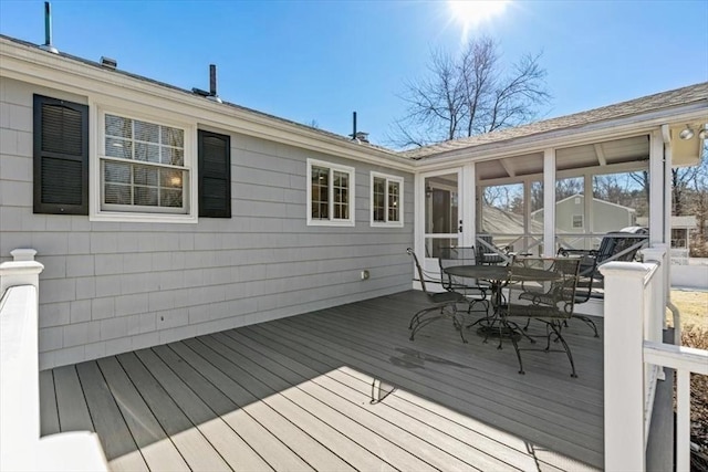 wooden deck with outdoor dining area and a sunroom