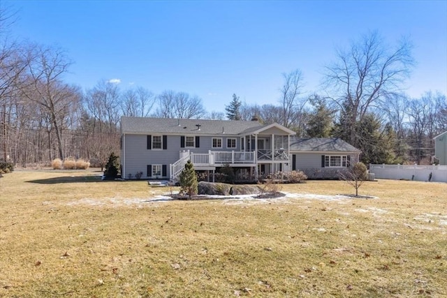 rear view of property featuring a yard, fence, and a wooden deck