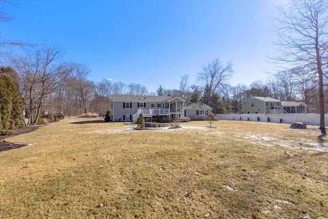 rear view of property featuring a lawn and fence