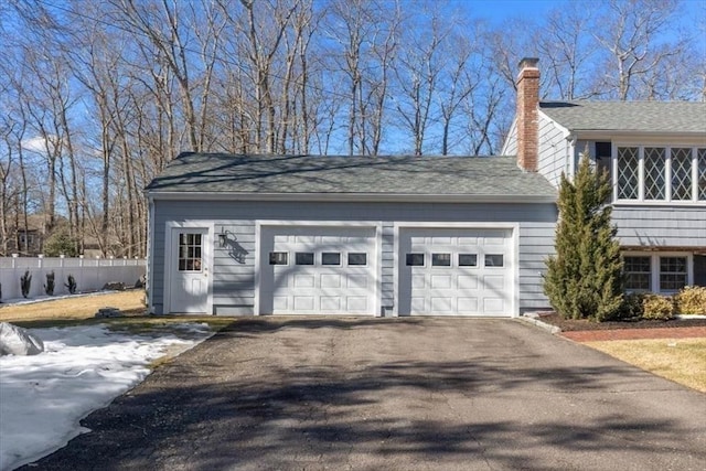 garage featuring driveway and fence