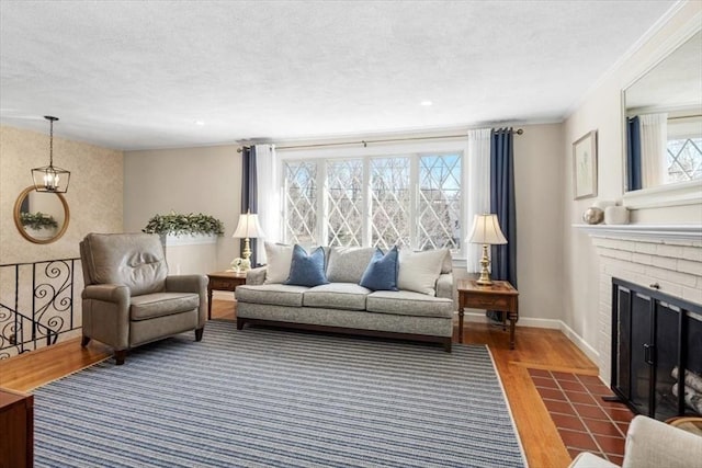 living room featuring a brick fireplace, dark wood-type flooring, baseboards, ornamental molding, and a textured ceiling