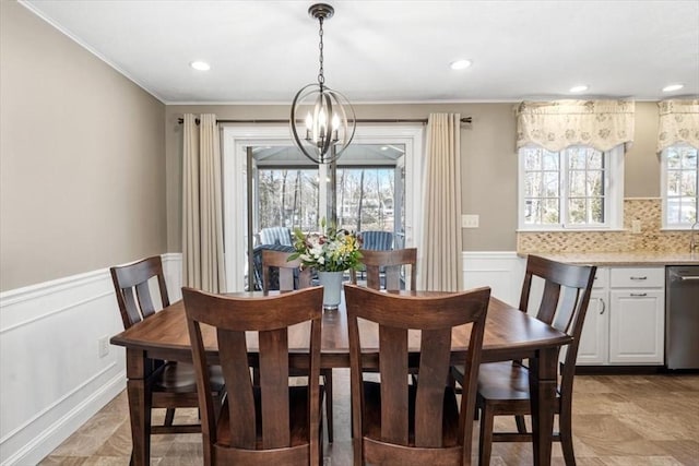 dining space with an inviting chandelier, recessed lighting, a wainscoted wall, and ornamental molding